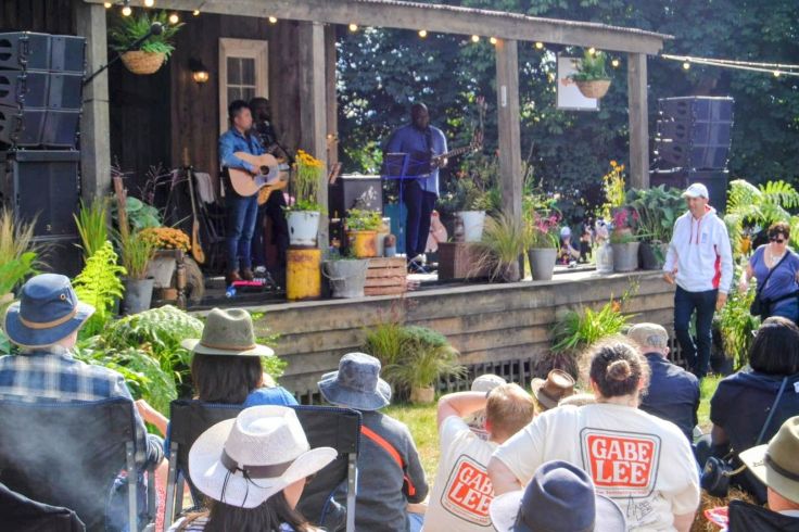 Gabe Lee performing on outdoor stage with an acoustic guitar, at Long Road festival